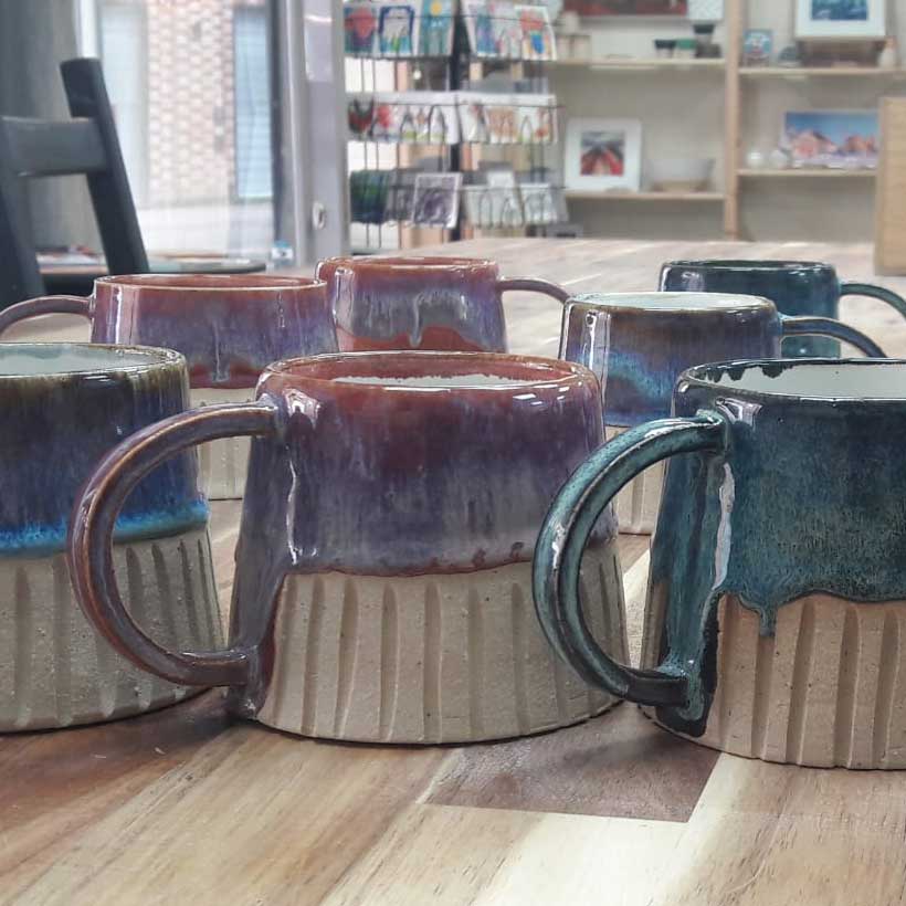 A new batch of glazed mugs just out of the kiln on the workbench at The Potter's Wheel.